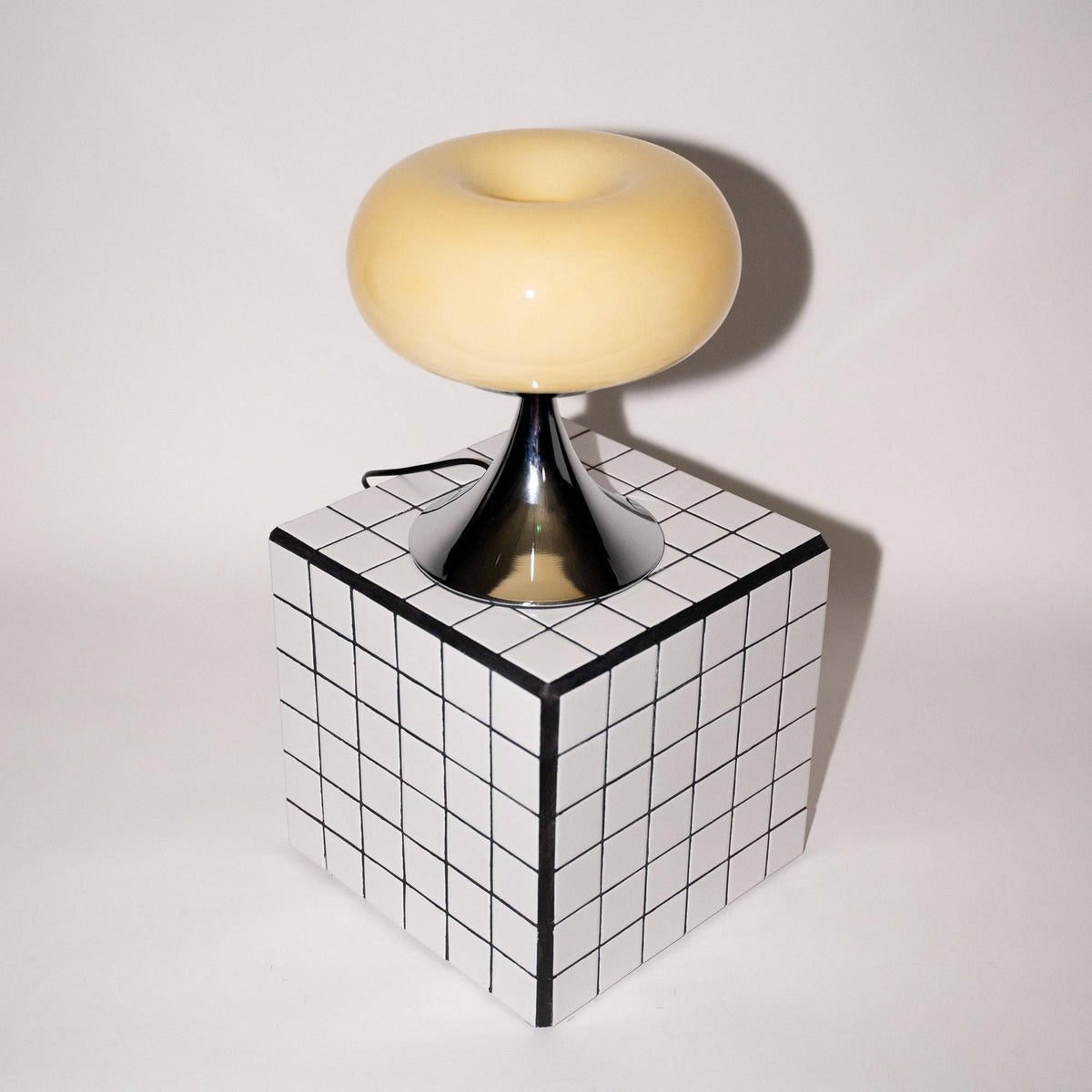 Retro bordlampe med ecru glas og metallisk fod placeret på et moderne flisebord. Et stilfuldt valg til mid-century moderne indretning.