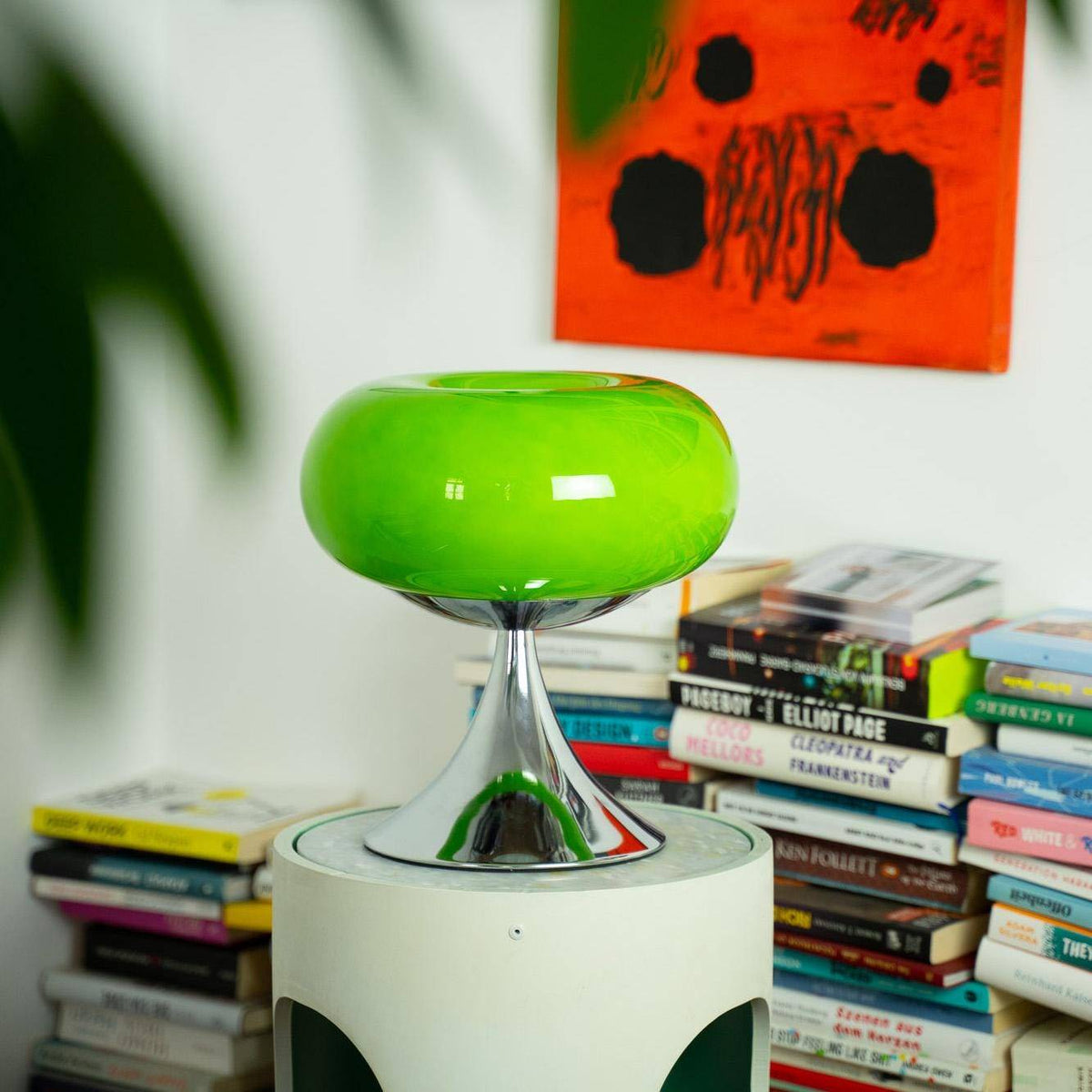 Retro glas bordlampe i grøn vintage stil fra GLOW UP STUDIO placeret på et moderne bord med bøger i baggrunden. Perfekt til stueindretning.