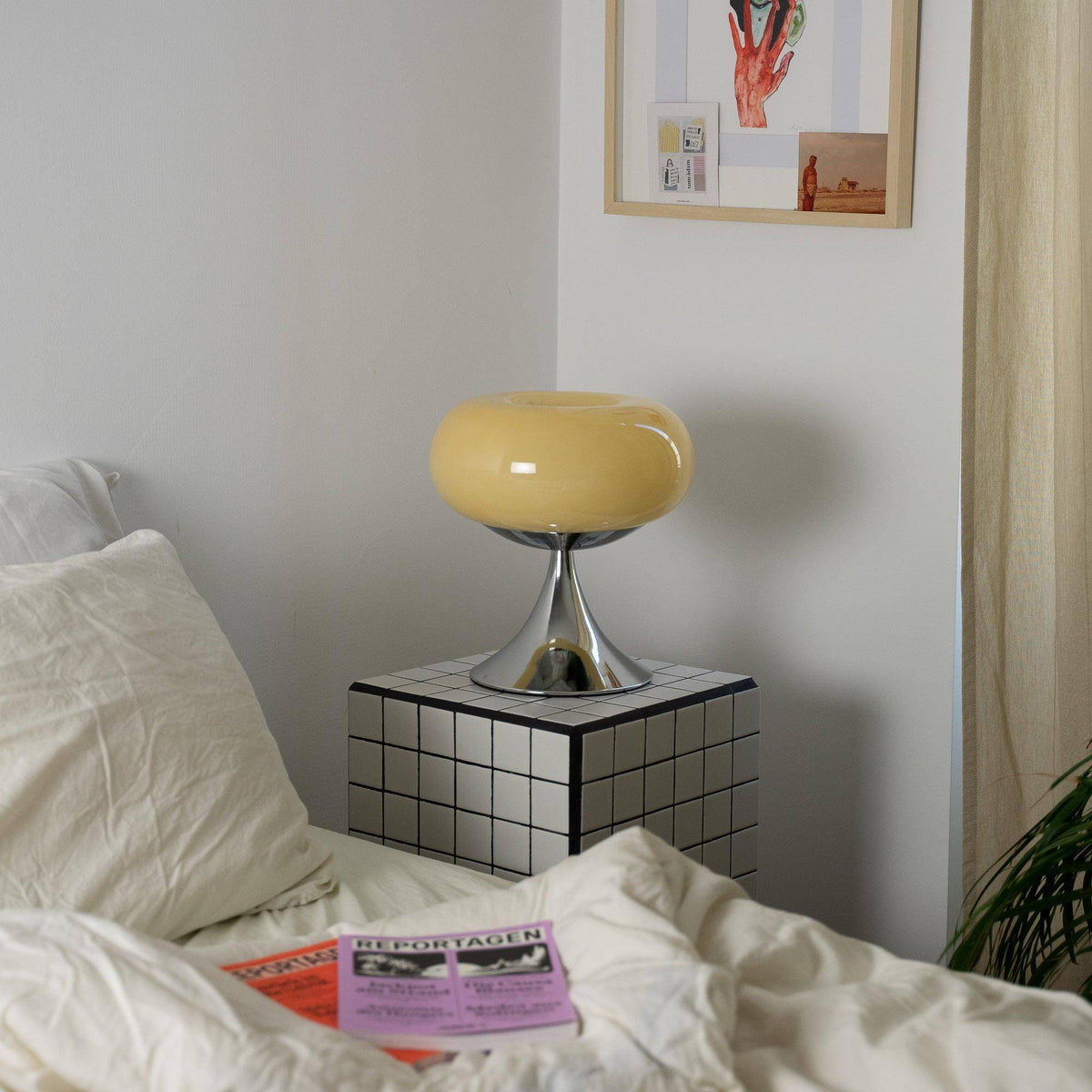 Design bordlampe i skandinavisk retrostil placeret på et flisebord i et stilfuldt soveværelse. Elegant kombination af funktion og æstetik.