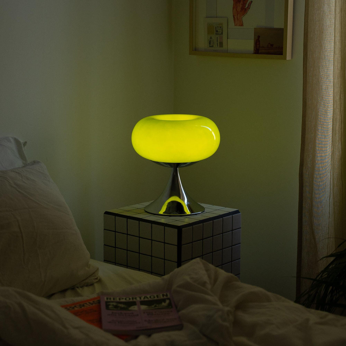 Retro bordlampe i grøn tændt på et natbord, skaber en blød belysning i soveværelset. Ideel til hyggelig stemning.