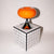 Orange retro lampe i glas med kromfod i 60'er stil, placeret på en ternet piedestal. Vintage design fra GLOW UP STUDIO til stilfuld indretning.