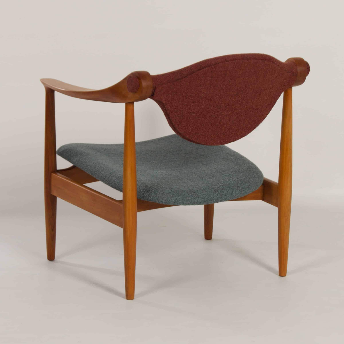 Bagside af restaureret dansk lænestol i træ med ryglæn i burgundy. Klassisk 1960’er design med skulpturelle detaljer.