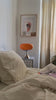 Orange retro lampe i glas på natbord i et stilfuldt soveværelse. Skaber en elegant og hyggelig atmosfære med vintage design.