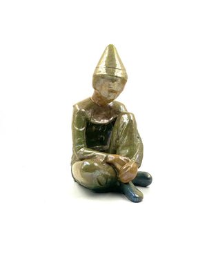 Green ceramic figure of a seated boy, created by Giordano Tronconi
