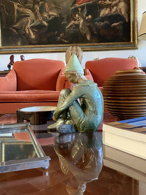 Green ceramic figure of a seated boy, created by Giordano Tronconi