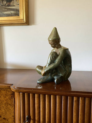 Green ceramic figure of a seated boy, created by Giordano Tronconi