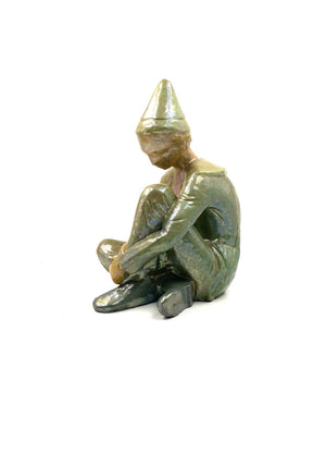 Green ceramic figure of a seated boy, created by Giordano Tronconi