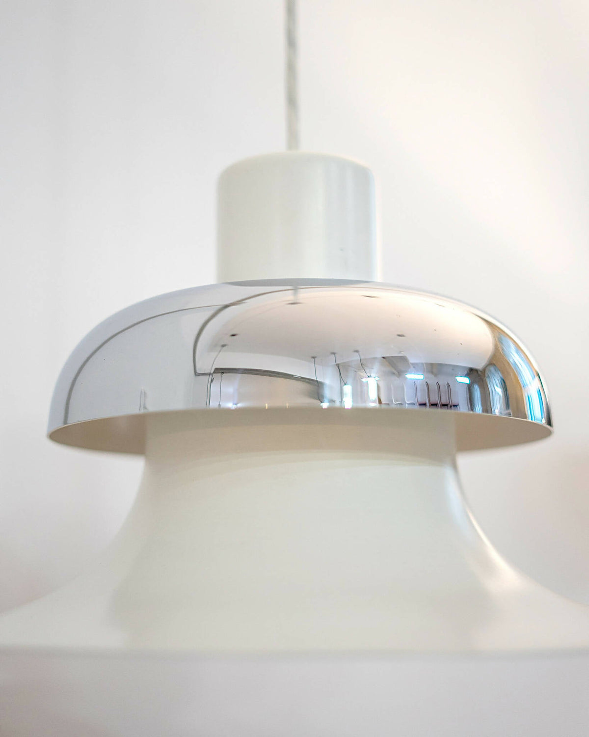 Nærbillede af Mandalay pendellampens blanke kromdetaljer og hvide cylinderform. Shop Mandalay pendellampe fra Louis Poulsen I SPLISH.