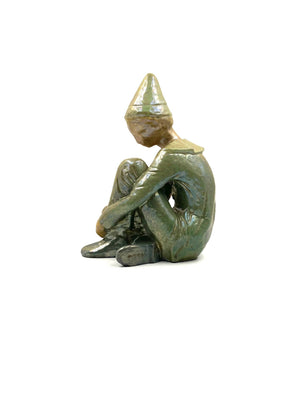 Green ceramic figure of a seated boy, created by Giordano Tronconi