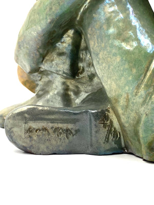 Green ceramic figure of a seated boy, created by Giordano Tronconi