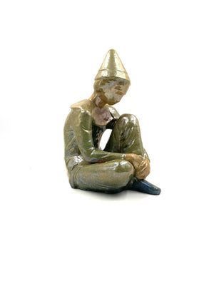 Green ceramic figure of a seated boy, created by Giordano Tronconi