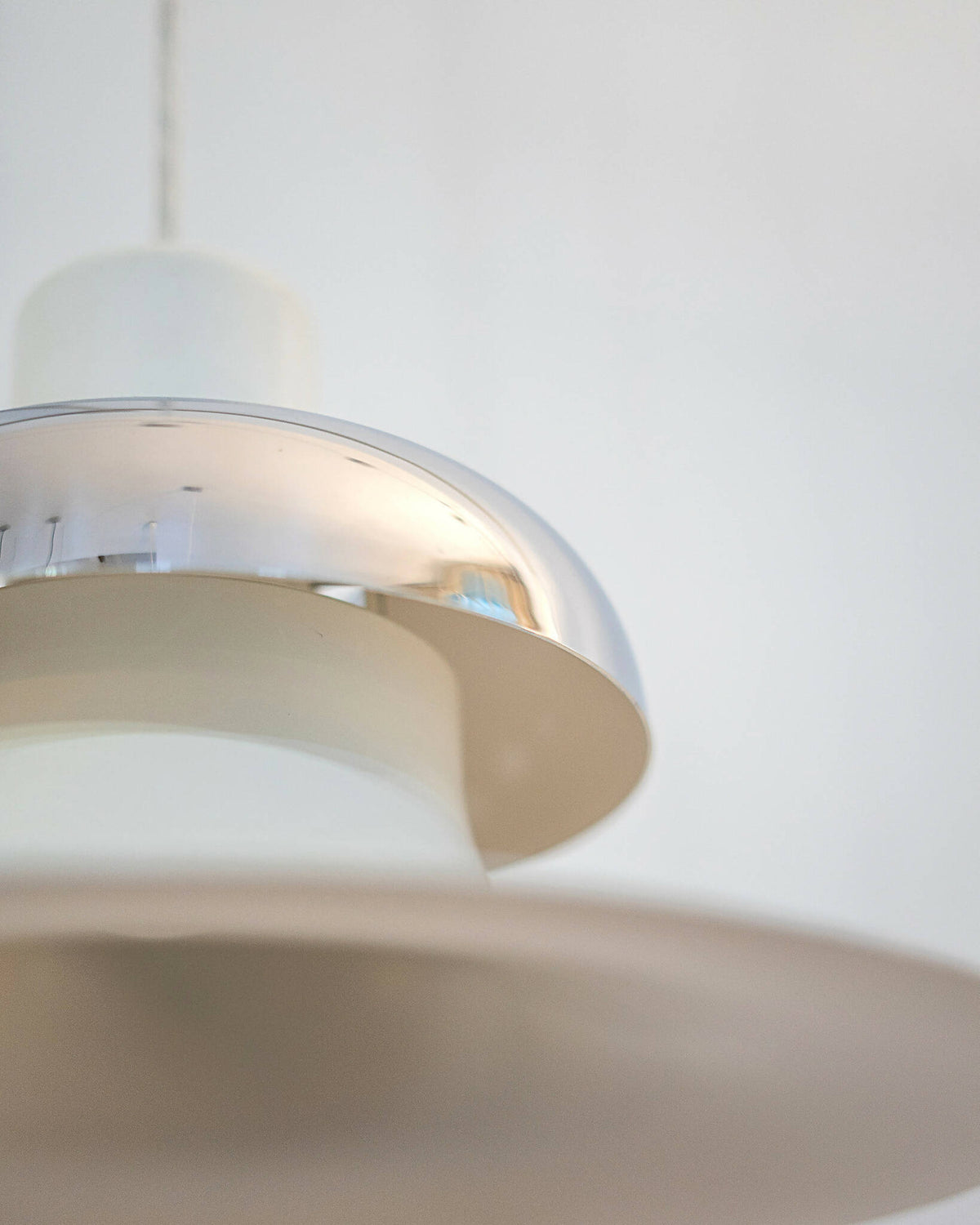 Sidevinkel af Mandalay pendellampe med fokus på lampens bølgede skærm og metalliske element. Shop Mandalay pendellampe fra Louis Poulsen I SPLISH.