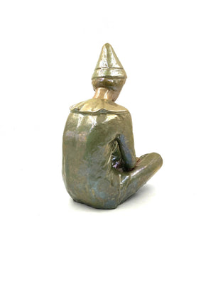 Green ceramic figure of a seated boy, created by Giordano Tronconi