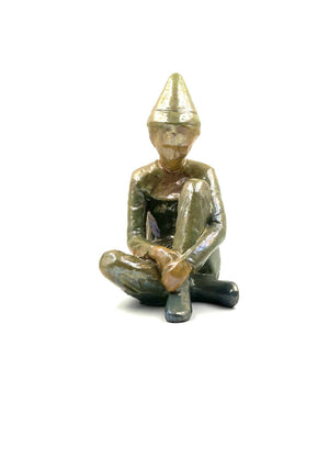 Green ceramic figure of a seated boy, created by Giordano Tronconi