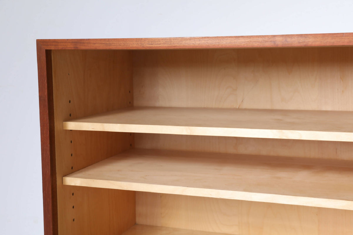 Indvendig visning af Poul Hundevad skænk med lyse træhylder. Justerbare hylder giver fleksibel opbevaring i dette vintage møbel.